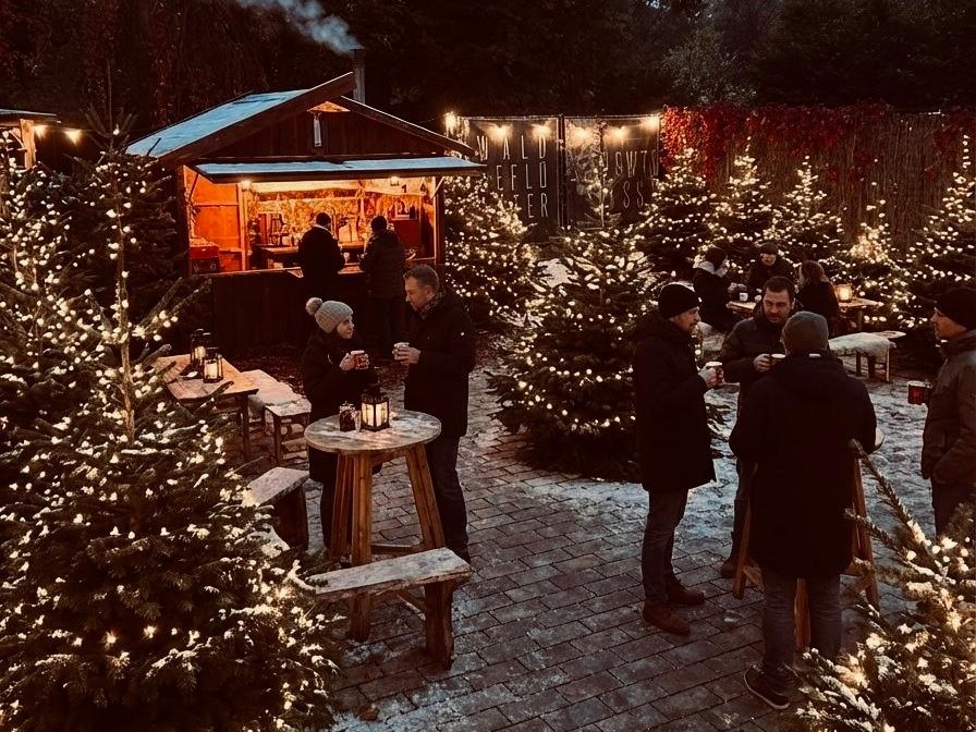 Winterwald: Glühweinstand und beleuchtete Tannen im Schnee